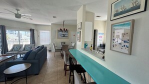 A spacious living area with a sofa, chairs, a dining table, and a kitchen counter. - Beachside House with 2 Floors (Jacksonville Beach)