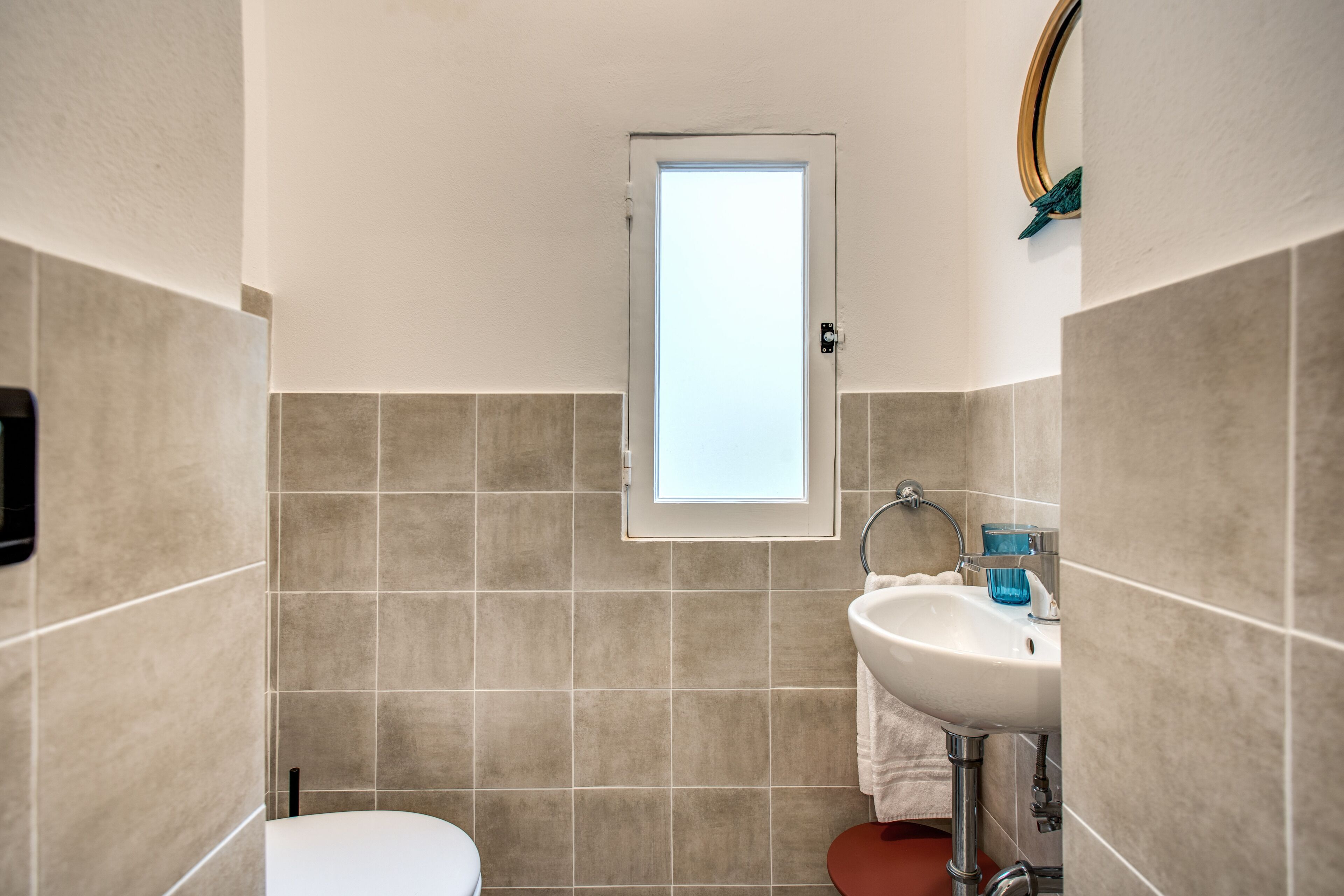 Een badkamer met toilet, wastafel en een raam.