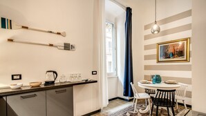 Una cocina moderna con piso de baldosas geométricas, una zona de comedor con una mesa redonda y sillas, y un cuadro en la pared.