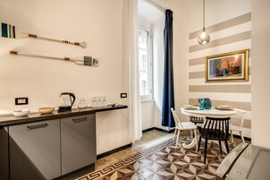 Una cocina moderna con piso de baldosas geométricas, una zona de comedor con una mesa redonda y sillas, y un cuadro en la pared.