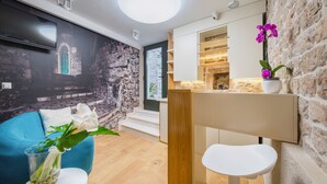 Un salon moderne avec un mur en pierre, un canapé bleu, une table blanche et un petit tabouret blanc.