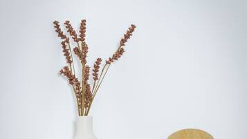 A shelf with three vases: a tall white vase with dried flowers, a smaller white vase, and a wooden sculpture.