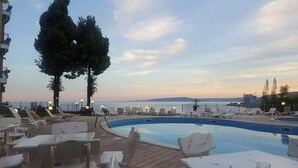 A pool area with lounge chairs and a view of the sea. - Hotel Helios (Balchik)