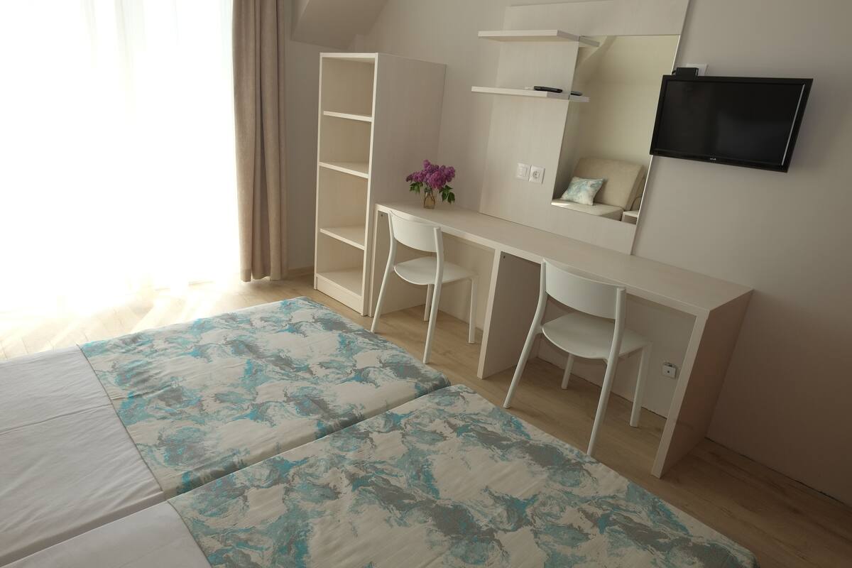 Un dormitorio con cama, escritorio, silla, armario y televisor.