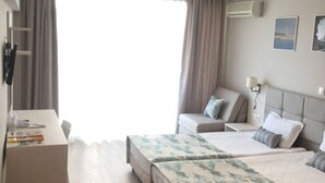 A hotel room with a bed, a desk, a chair, and a window with curtains. - Hotel Helios (Balchik)
