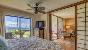 A hotel room with a bed, a television, a sliding glass door leading to a balcony with a view of the ocean. - Uninterrupted Ocean views, 70" of Entertainment (Wailuku)