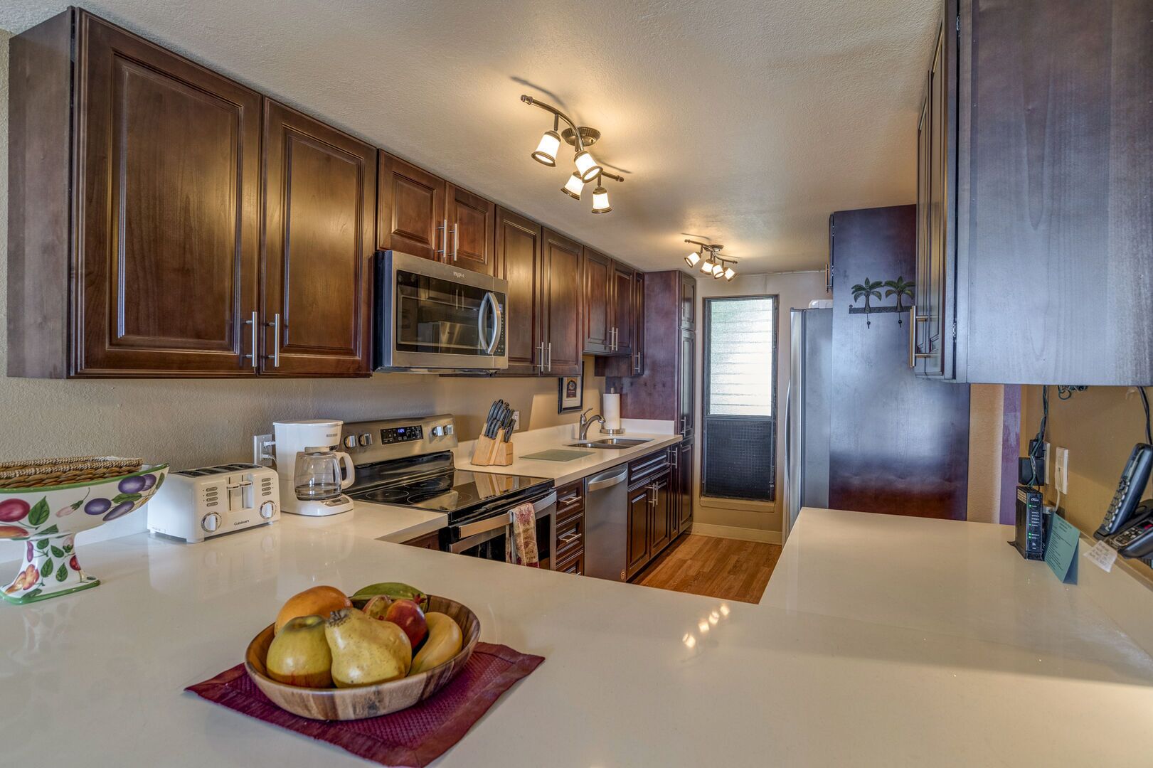 Una cocina moderna con armarios de madera, electrodomésticos de acero inoxidable y una isla central con un frutero.