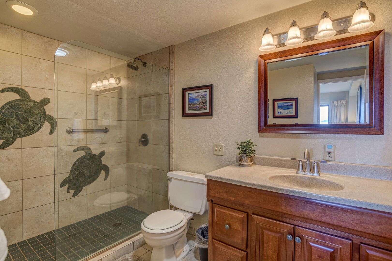 Une salle de bain avec une douche à parois de verre, des toilettes, un meuble-lavabo avec un miroir et un tableau encadré au mur.