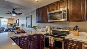 Una cocina moderna con armarios de madera oscura, electrodomésticos de acero inoxidable y una isla grande con un bol de fruta.