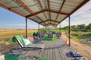 Ein überdachter Außenbereich mit Lounge-Möbeln und einem Tisch, eingebettet in eine natürliche Landschaft.