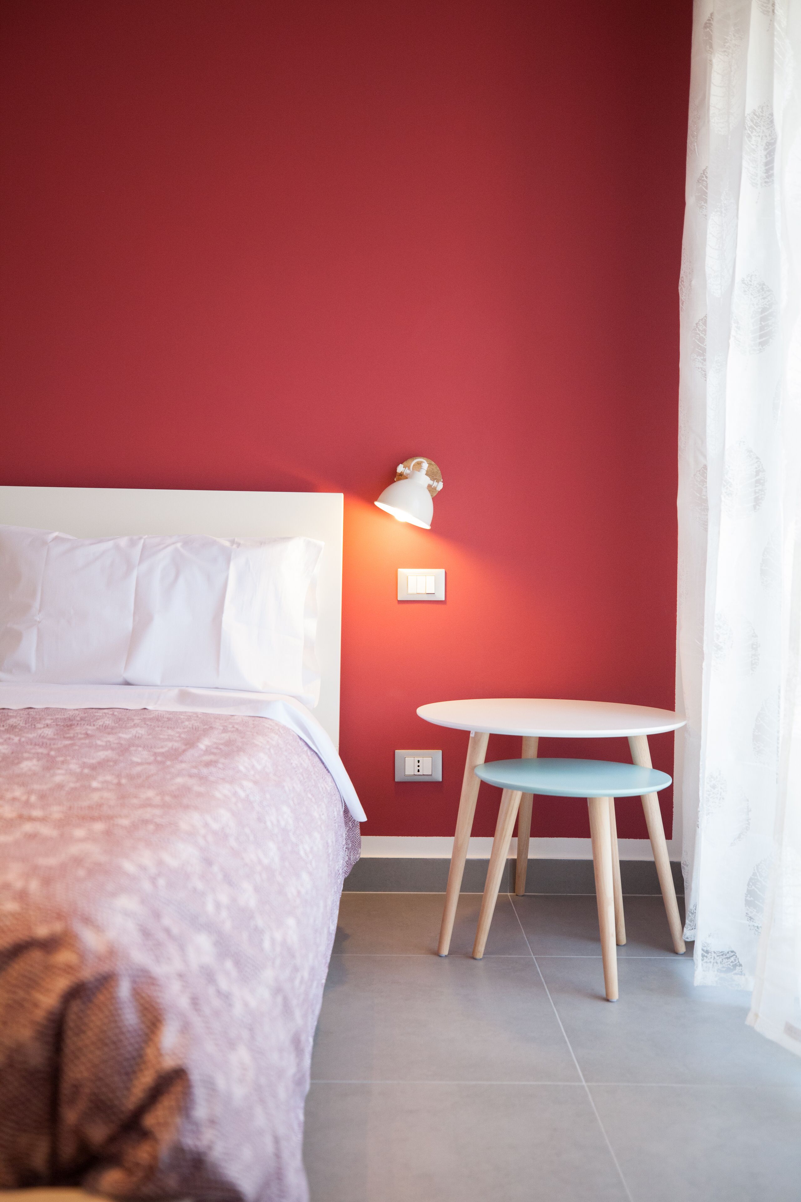 Habitación de hotel con cama, una mesita, una lámpara y ventana con cortinas.