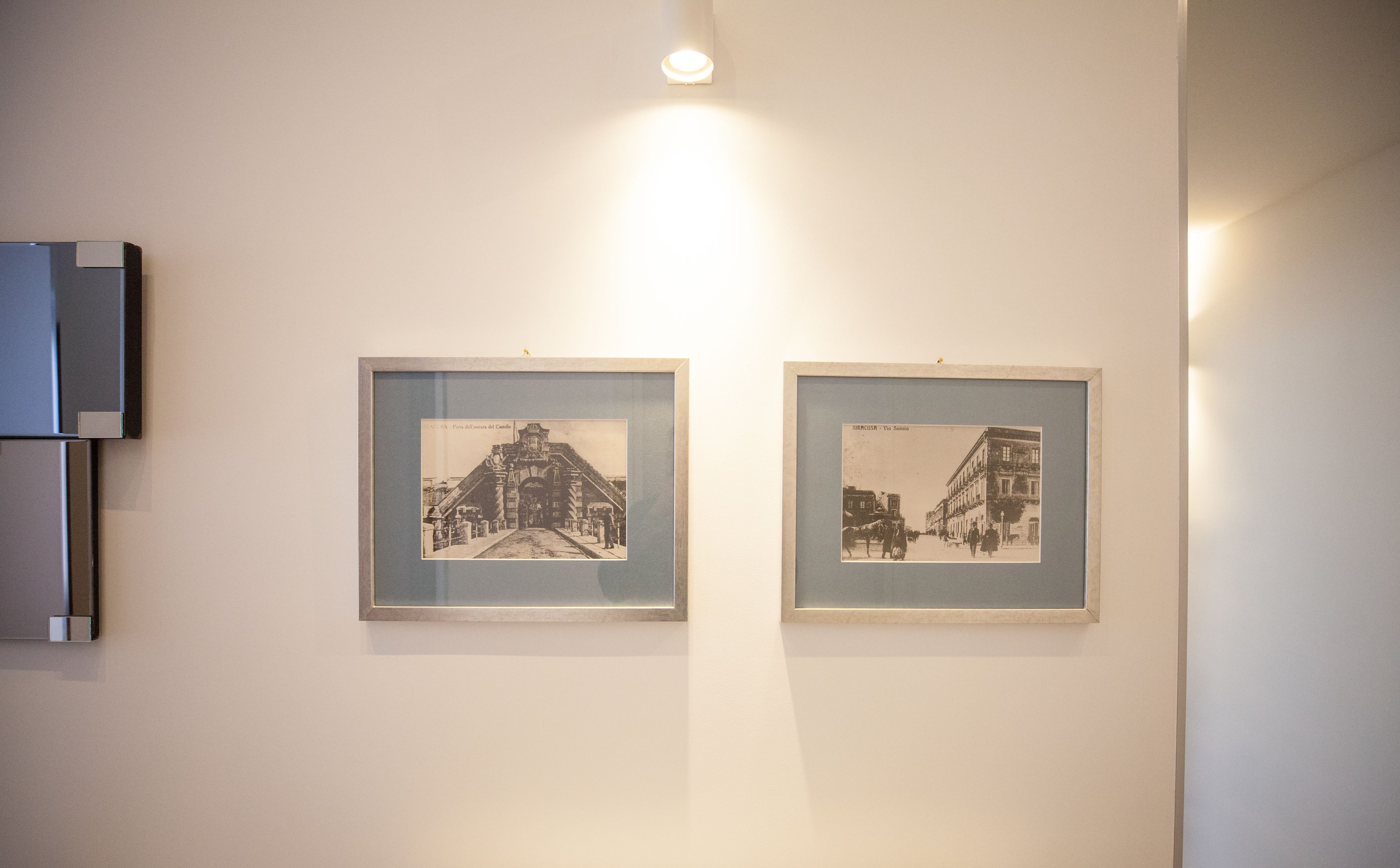 Two framed black and white photographs on a wall, one depicting a building with a dome and the other showing a street scene with buildings and people.