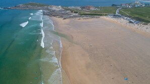 An aerial view of a beach with clear waters, a sandy shore, and a few buildings in the background. - 5 The Vista, Newquay -  Walk to Beach - Free Parking & WiFi - Sea & Beach Views (Newquay)
