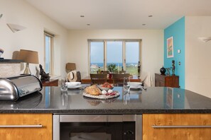 A modern kitchen with a large island, a dining area with a view, and a blue accent wall.