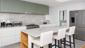 Une cuisine moderne dotée d’un îlot central, d’appareils électroménagers en acier inoxydable et d’un design minimaliste.