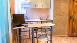 A compact kitchen with a microwave, toaster, and sink. There is a small table with a chair and a shelf with a microwave on it. - Studio in the center near the Botanical Garden (Pechers'kyi district)