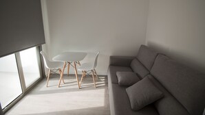 A modern living room with a grey sofa, a white table, and two white chairs. - Hostal Sa Vinya Suites (Sant Joan de Labritja)