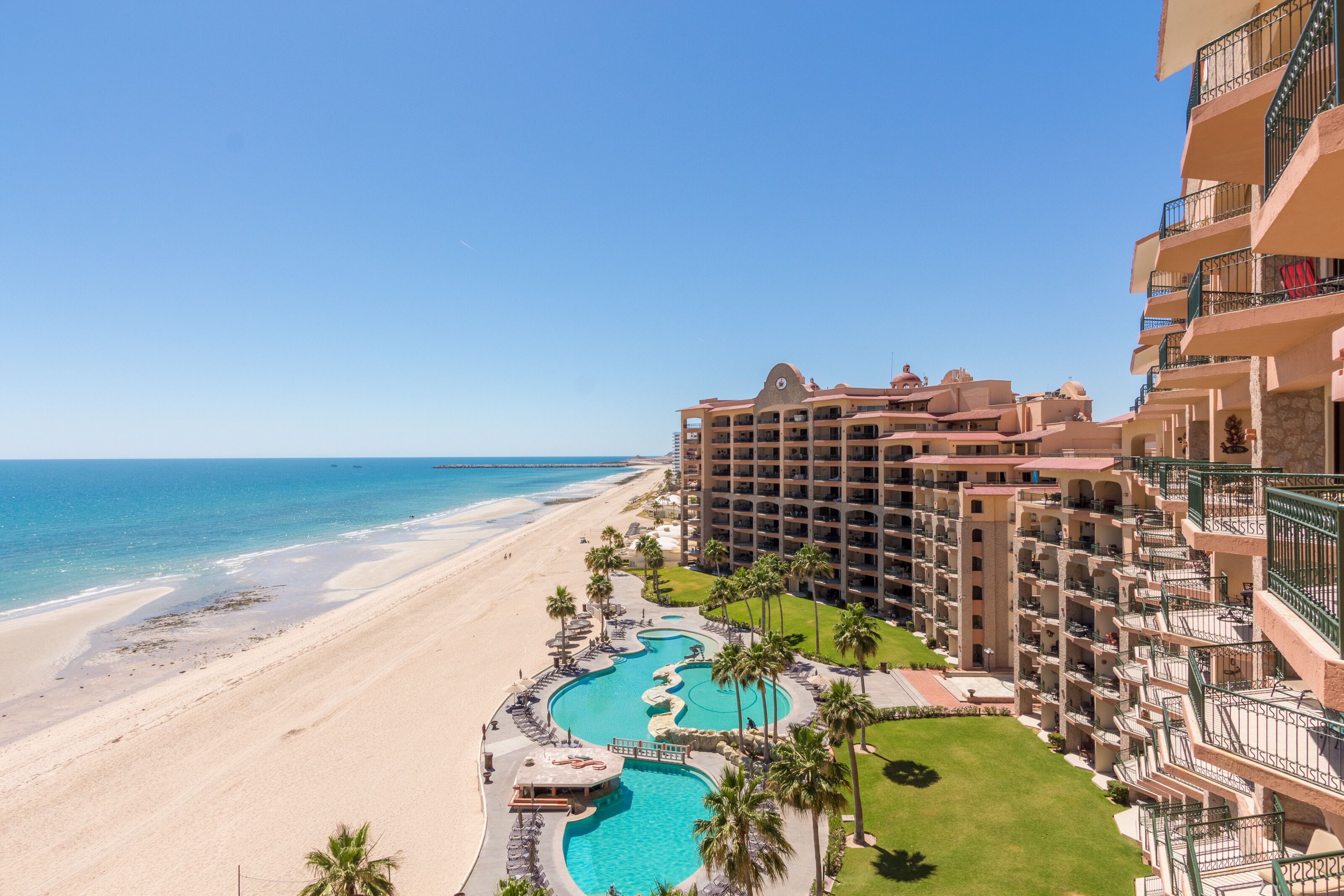 Een hotel met een zwembad, strand en uitzicht op de oceaan.
