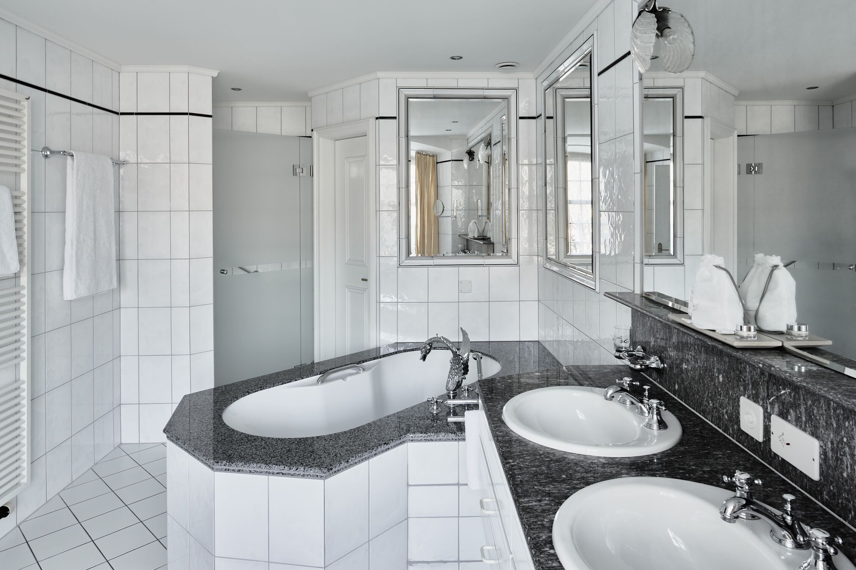 Une salle de bain moderne avec deux lavabos, un grand miroir et une baignoire.