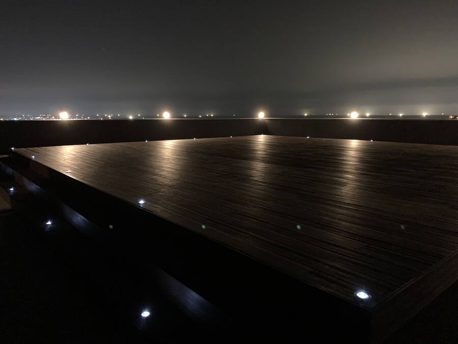 Amplia terraza de madera oscura con vista al horizonte urbano nocturno.