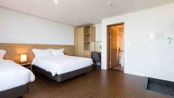 A hotel room with two beds, a desk, a chair, and a wardrobe.