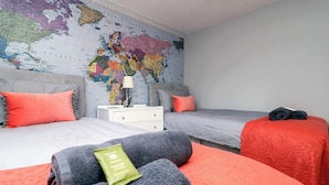 Una habitació d'hotel amb dos llits, un mapa del món a la paret i una tauleta de nit amb una làmpada.