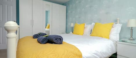 A bedroom with a bed, a wardrobe, a nightstand, and a lamp.