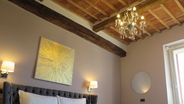 Un dormitorio con una cama grande, un candelabro, una lámpara de pared y un espejo redondo.