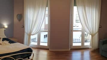 A bedroom with a bed, a nightstand, a green sofa, and a window with curtains.