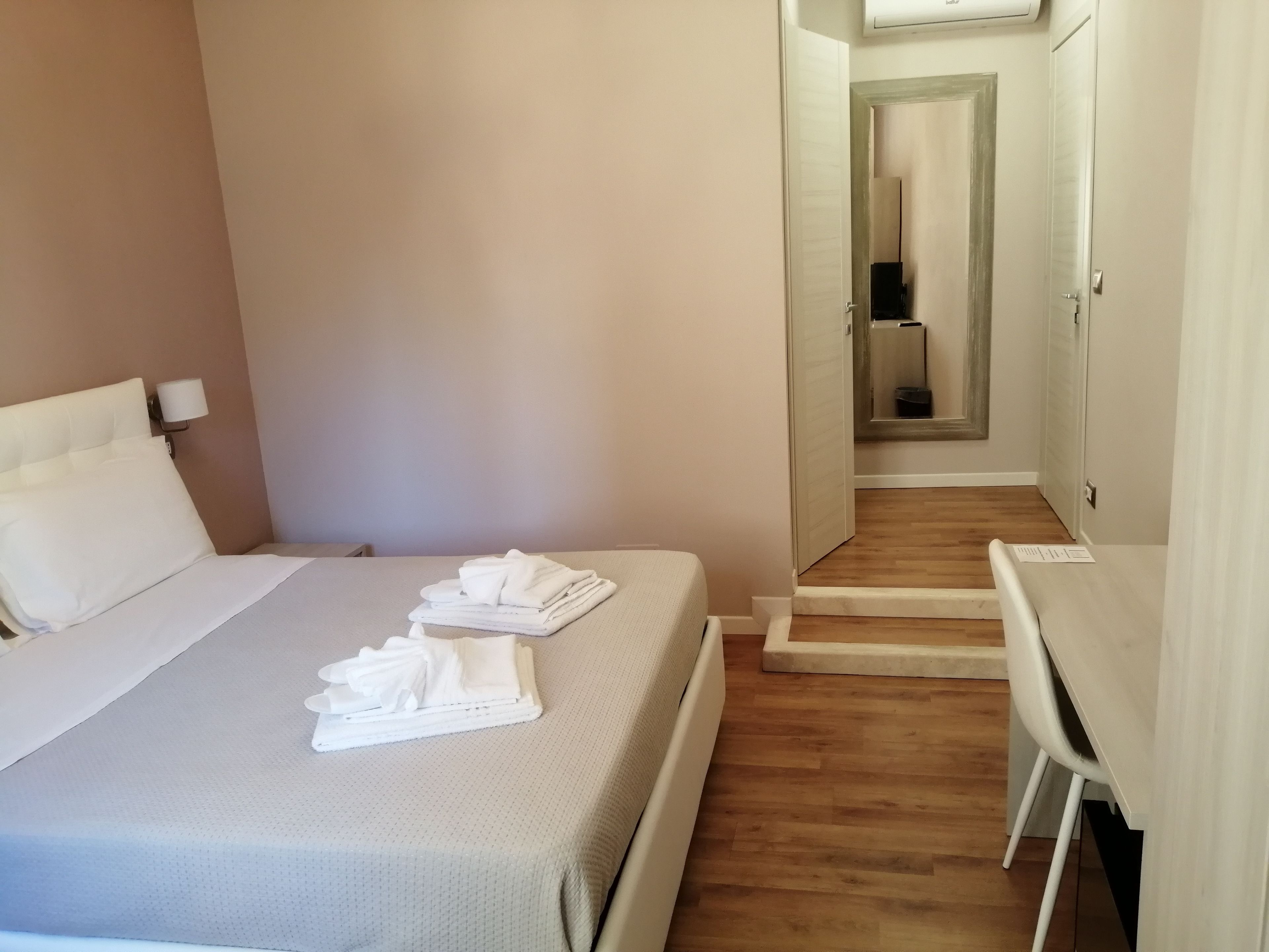 Quarto de hotel com cama, escrivaninha e cadeira.