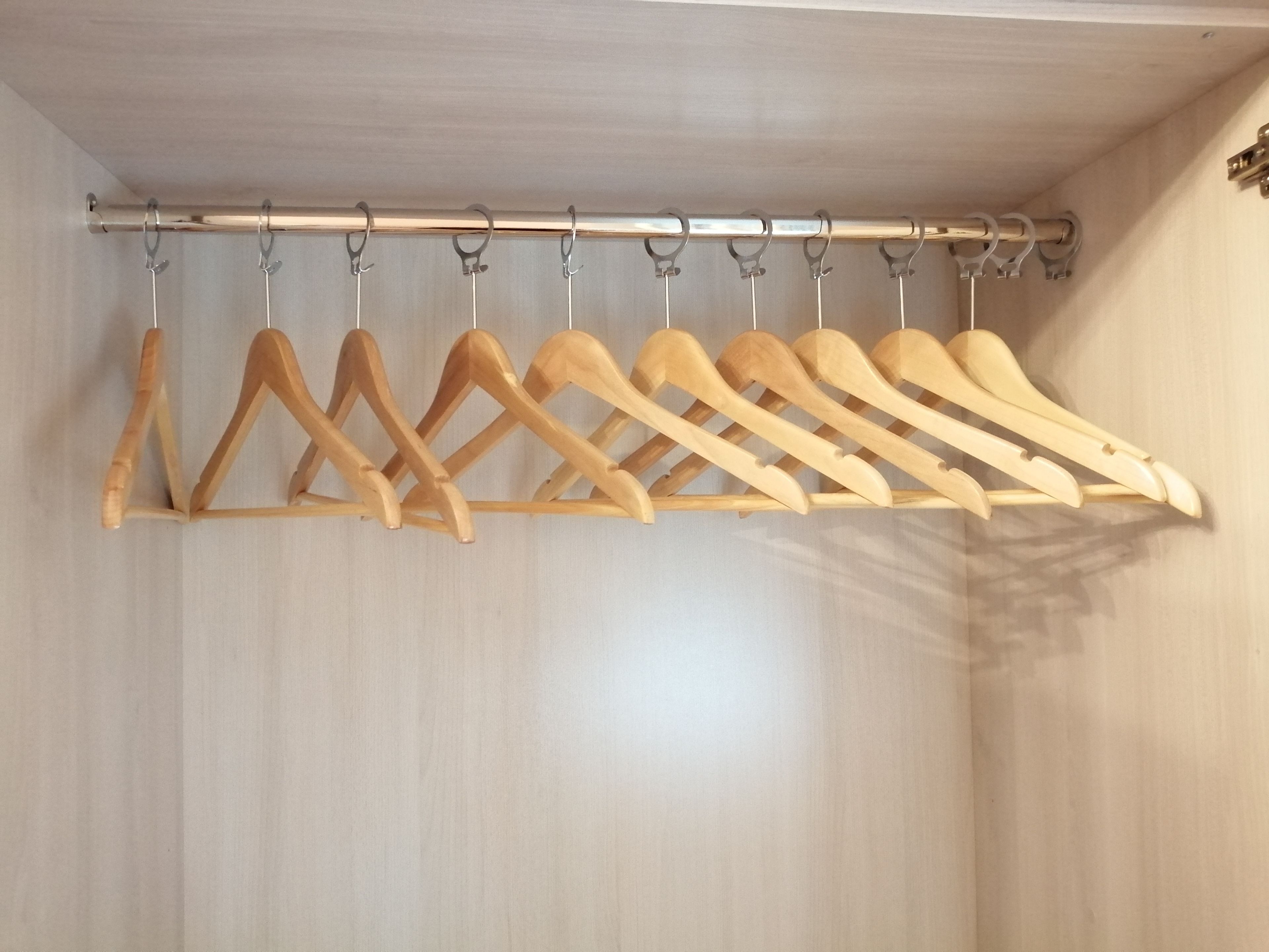 Un porte-manteau en bois, doté de plusieurs crochets, est fixé à un mur de couleur claire.
