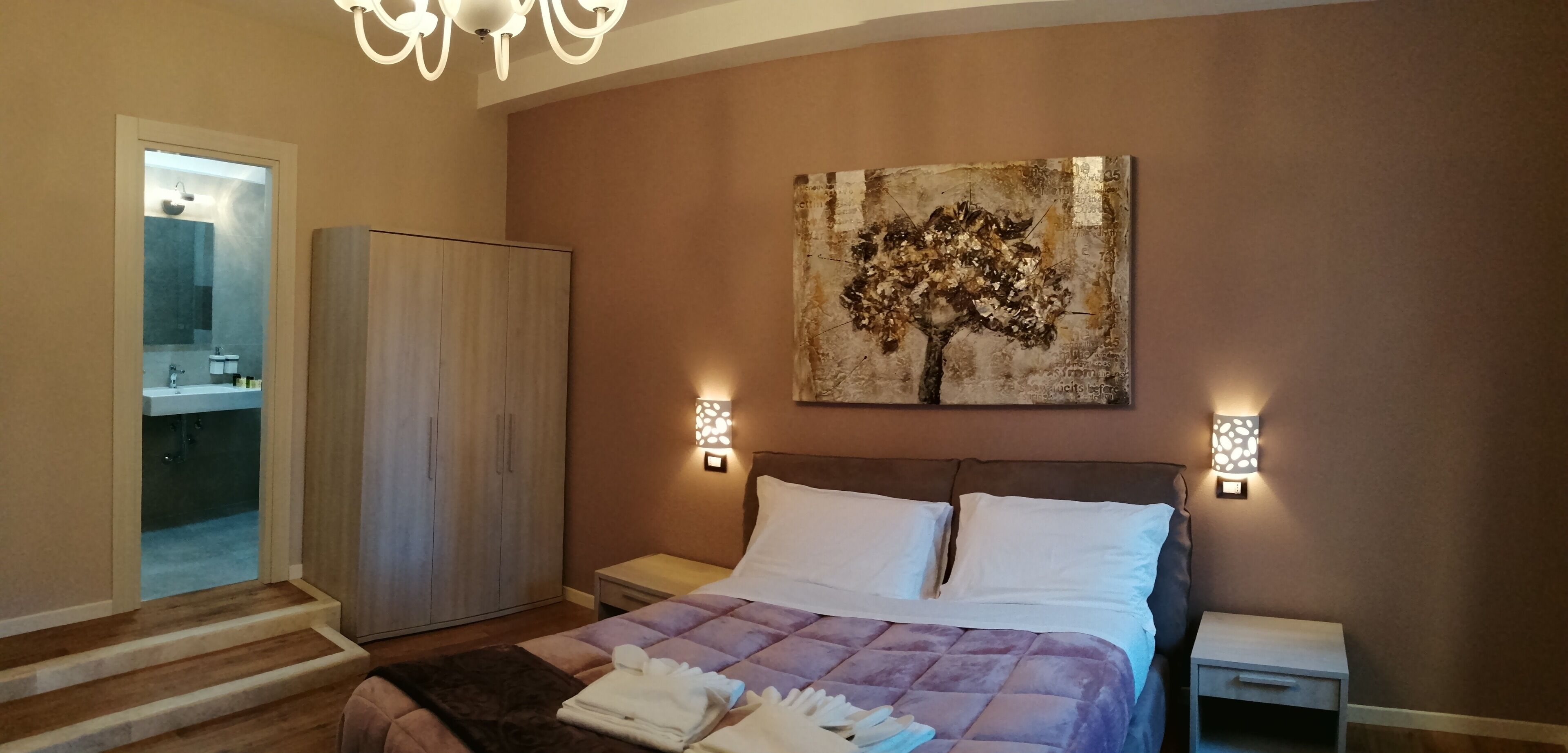 Une chambre à coucher avec un lit, des tables de chevet, une armoire et un tableau au mur.