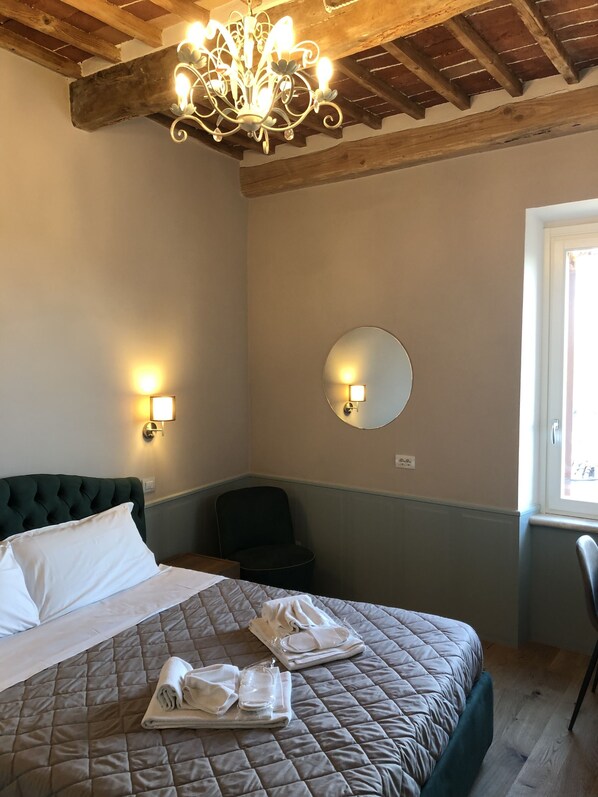 Un dormitorio con cama, espejo redondo, silla y candelabro.