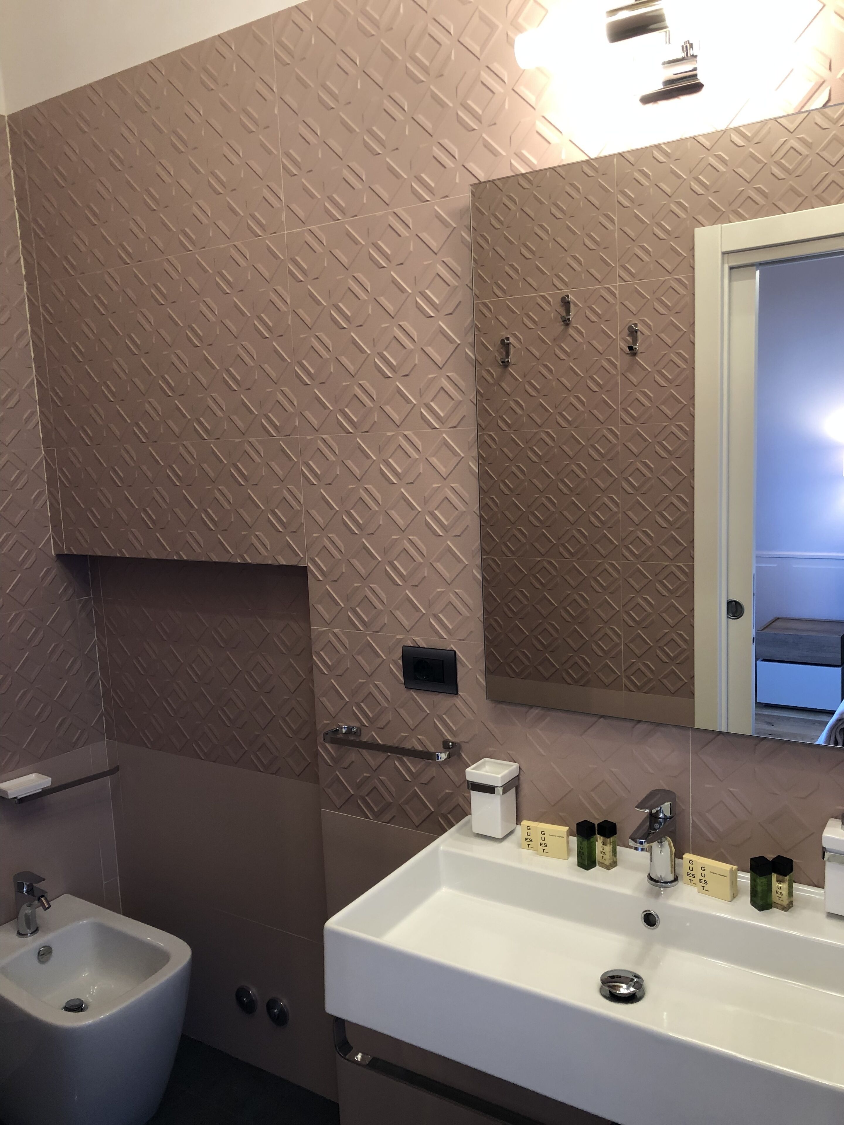 Un baño con lavamanos blanco, un bidé, toallero y espejo.