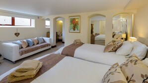 Habitación de hotel con dos camas, un sofá, una decoración con forma de corazón y un cuadro en la pared.