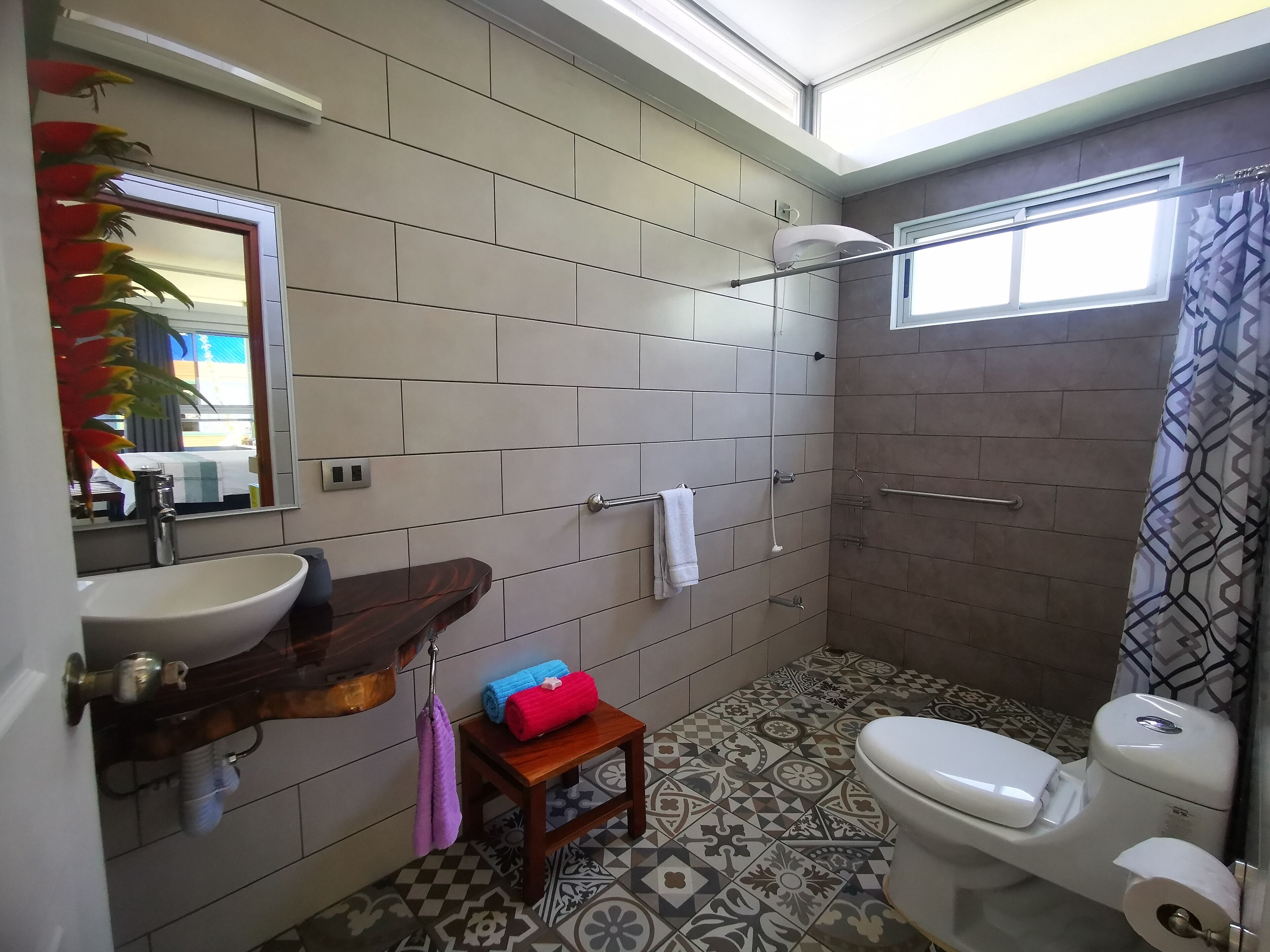 A bathroom with a sink, toilet, shower, and patterned floor tiles.