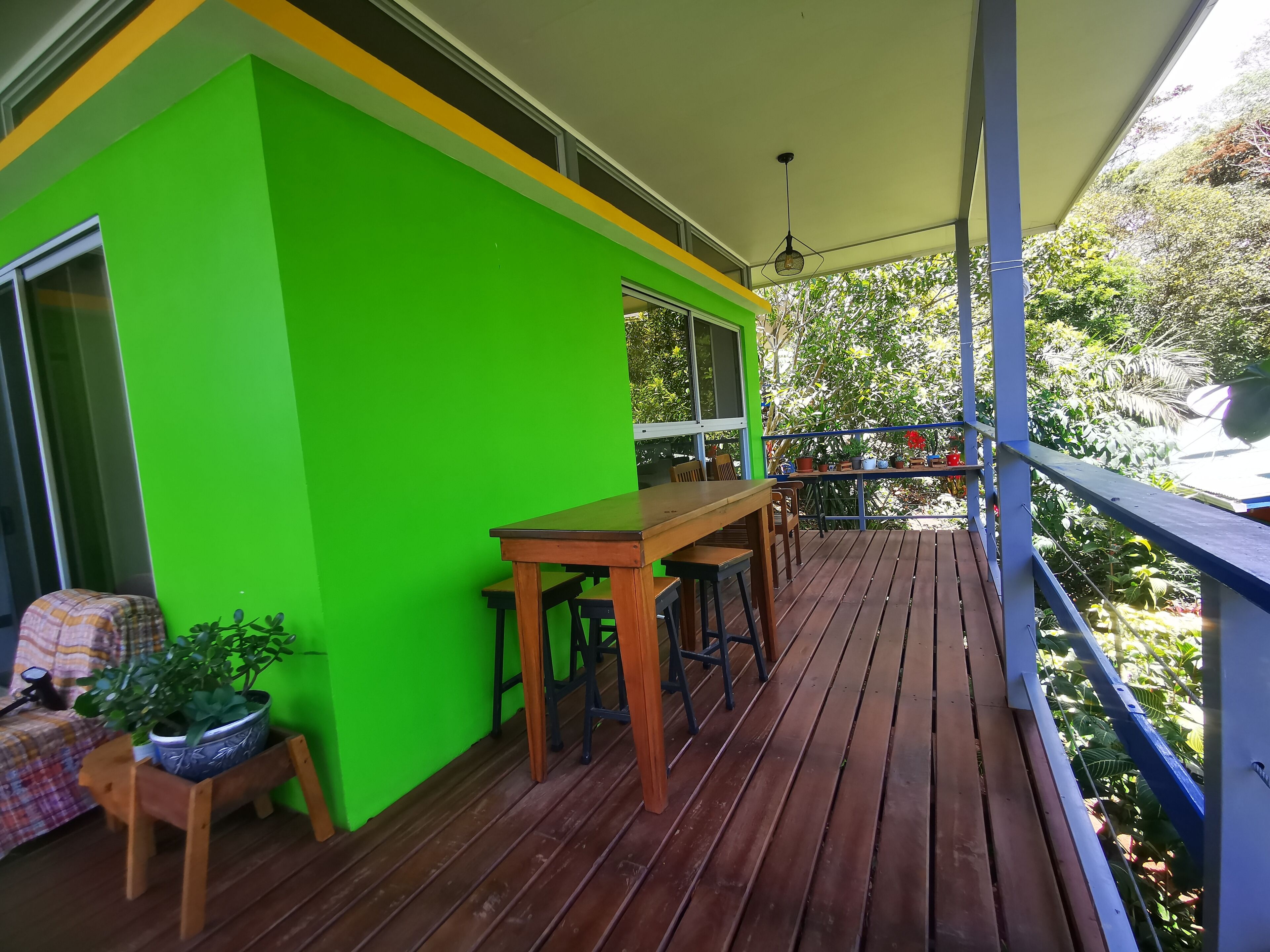 A wooden deck with a green wall, a table, and chairs.