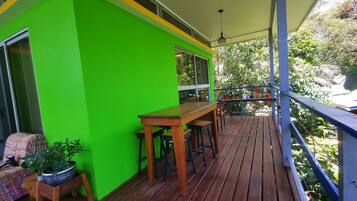 A wooden deck with a green wall, a table, and chairs.