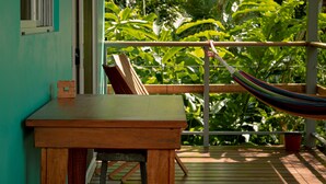 A wooden table and bench on a balcony with a hammock, overlooking lush greenery. - Agutipaca B&B (Río Naranjo)