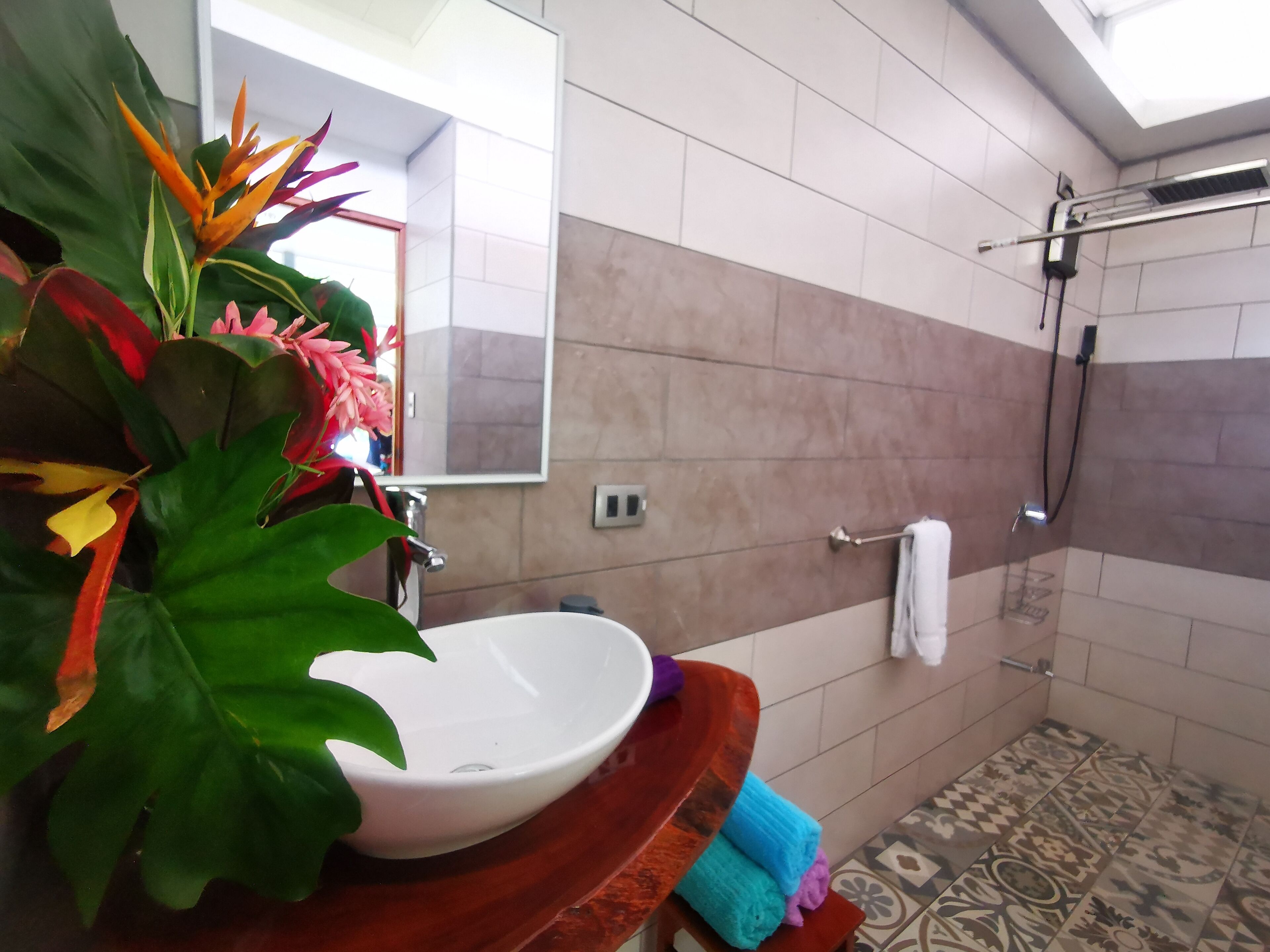 A bathroom with a white sink, a shower, and a large mirror.