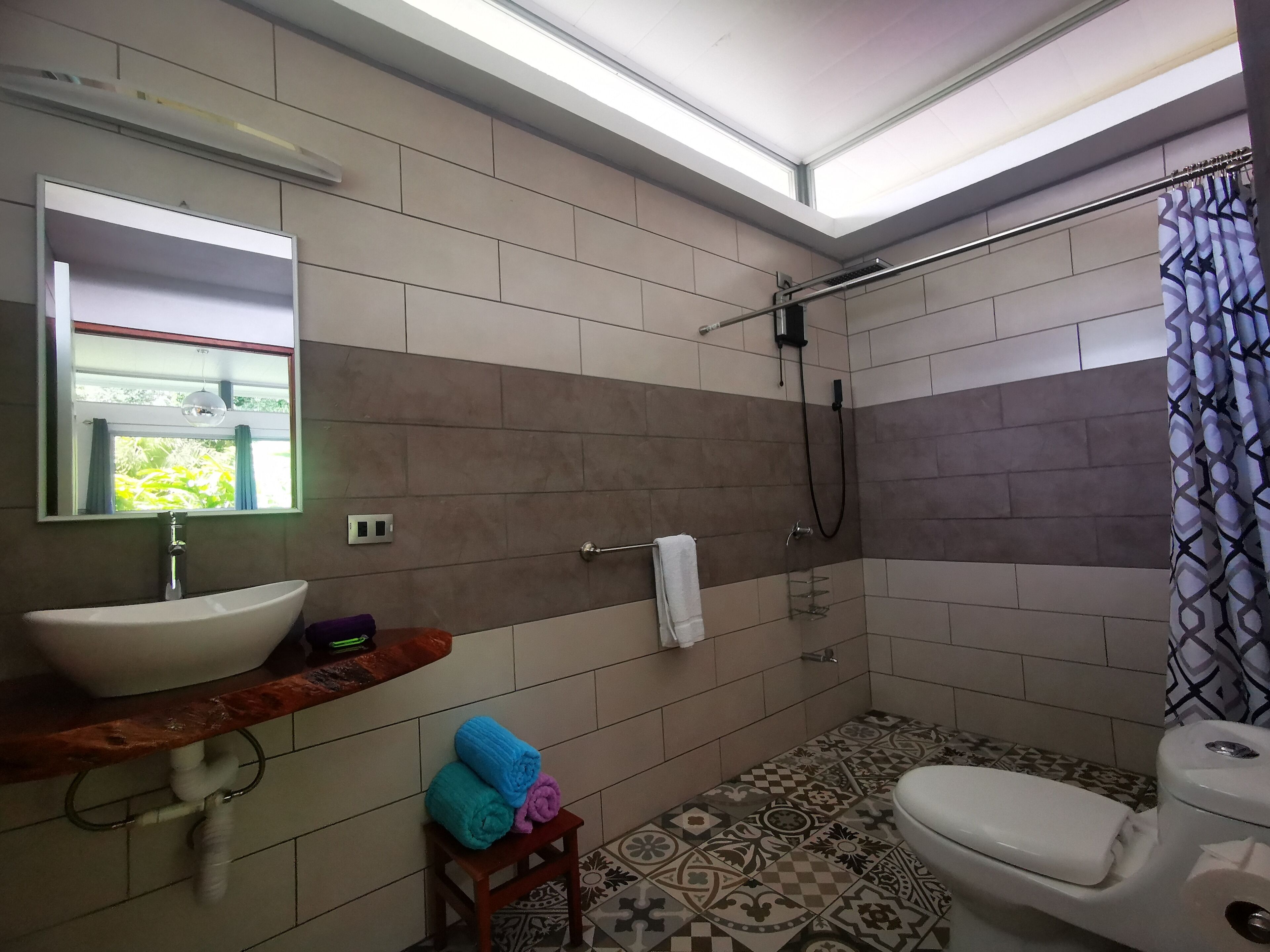 Ein Badezimmer mit Waschbecken, Spiegel, Dusche und Toilette.