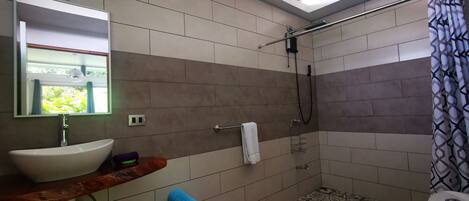 A bathroom with a sink, mirror, shower, and toilet.