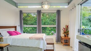 A bedroom with a bed, a wooden bench, a small table with a vase, and a refrigerator. - Agutipaca B&B (Río Naranjo)