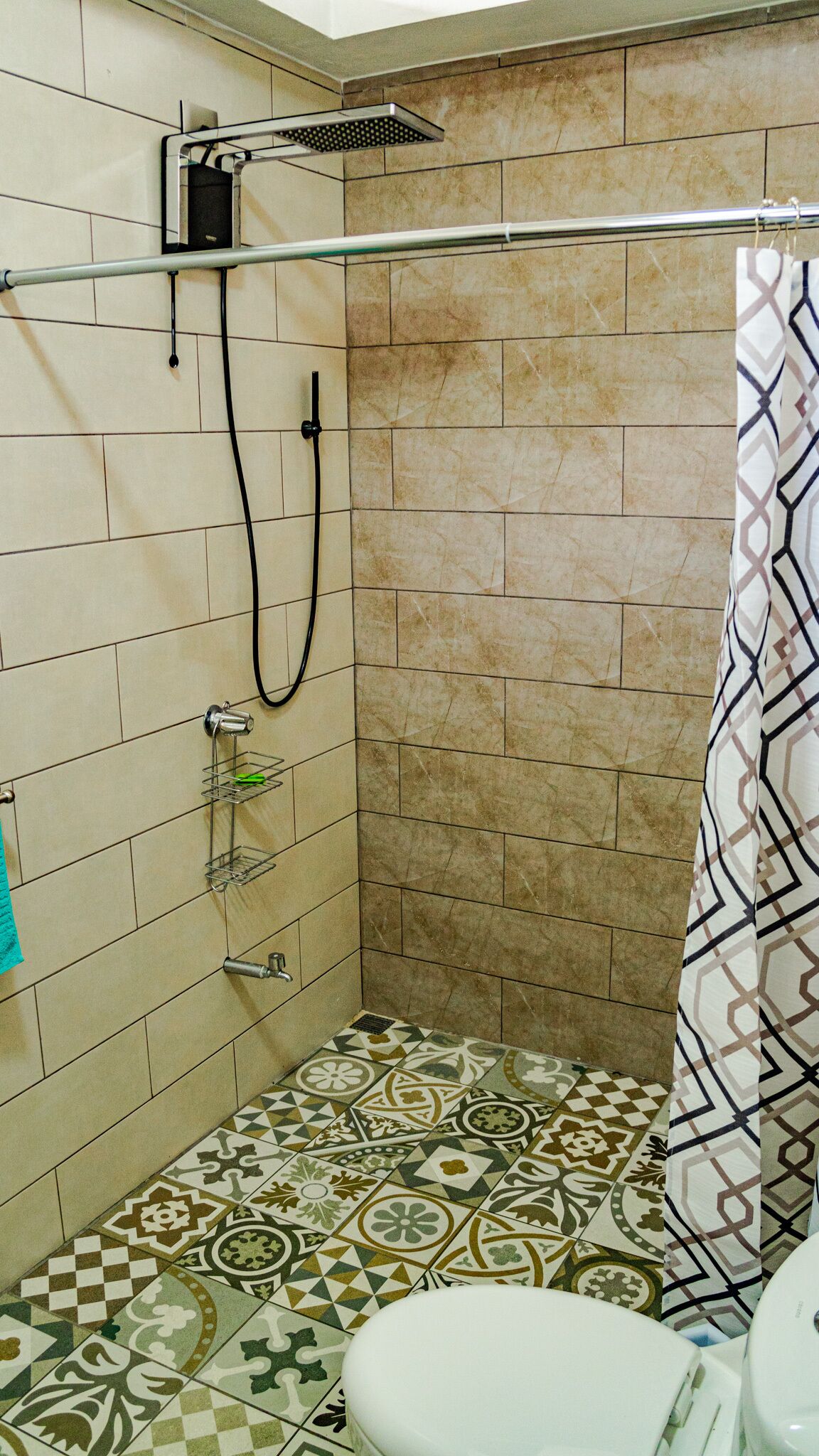 Un baño pequeño con azulejos, que incluye una ducha, un inodoro y un perchero para toallas.