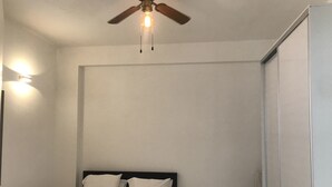 Ein Schlafzimmer mit einem Bett, einem Deckenventilator und einer Wandleuchte.