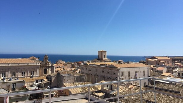 A coastal cityscape with historic buildings and a clear view of the sea.