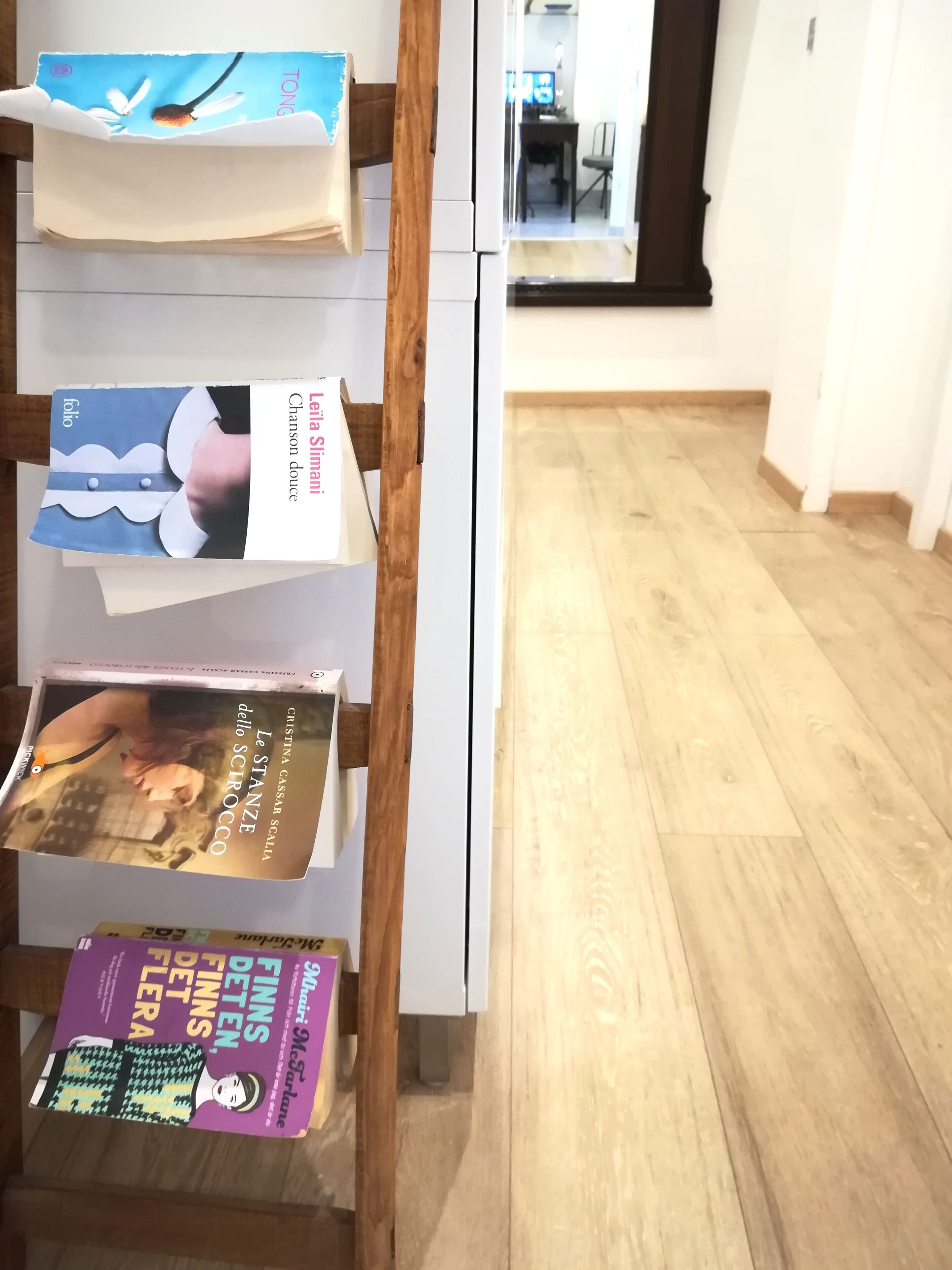 A bookshelf with books and a wooden ladder.