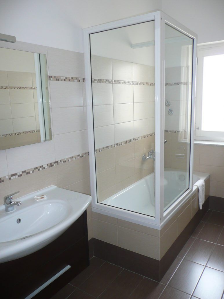 A bathroom with a glass-enclosed shower, a sink, and a bathtub.