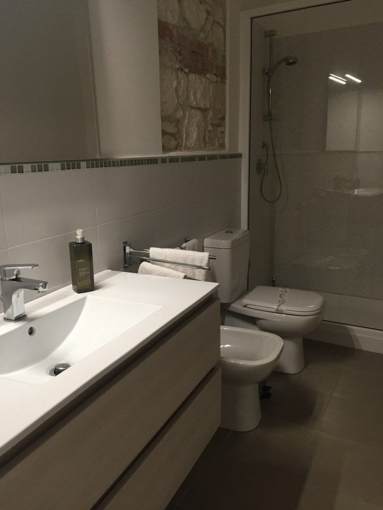 A modern bathroom with a large sink, toilet, bidet, and shower.