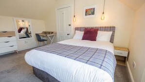 A bedroom with a bed, a desk, a chair, a dresser, and a mirror. - Inverness (Inverness)